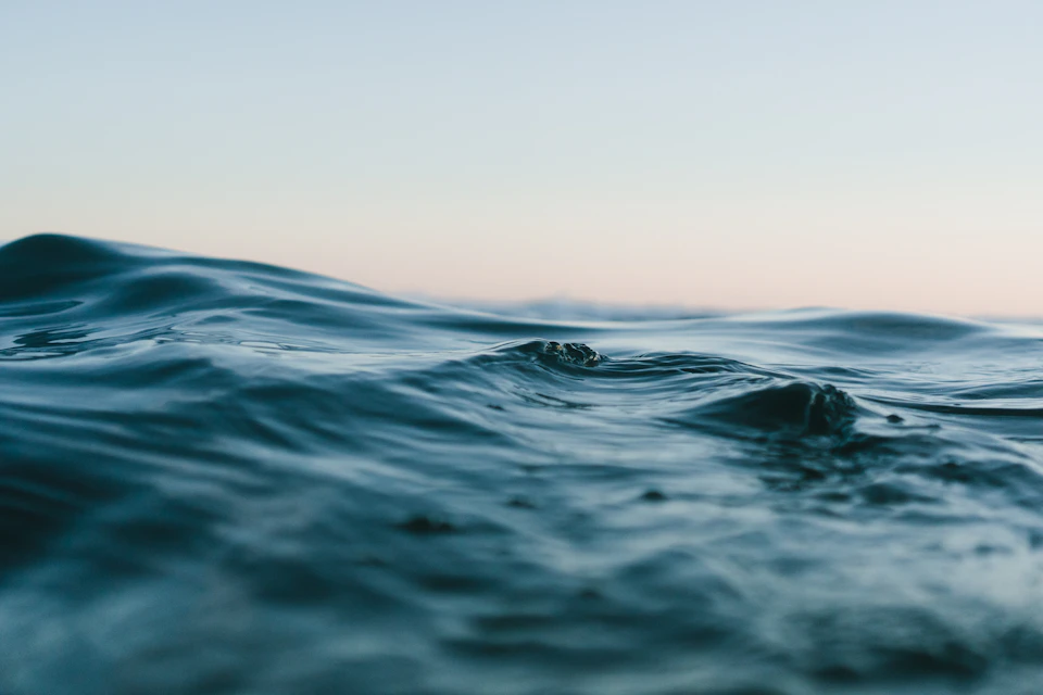 Soft blue ocean waves beneath a pale sky